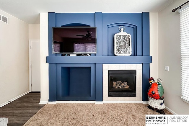 details featuring a ceiling fan, visible vents, a fireplace, wood finished floors, and baseboards