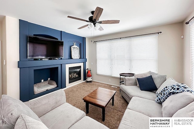 living area with carpet floors, ceiling fan, a wealth of natural light, and a tile fireplace