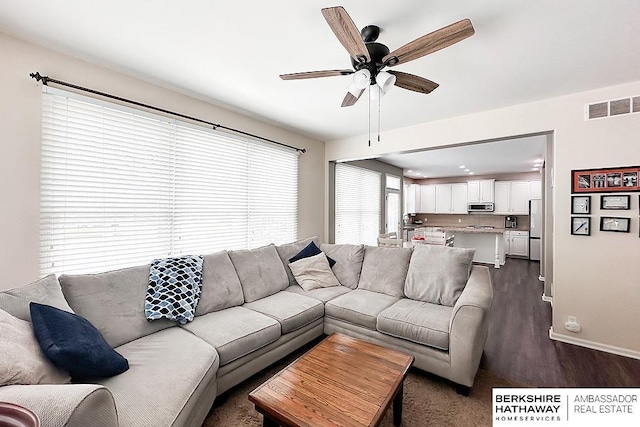 living area with visible vents, a ceiling fan, baseboards, and dark wood-style floors
