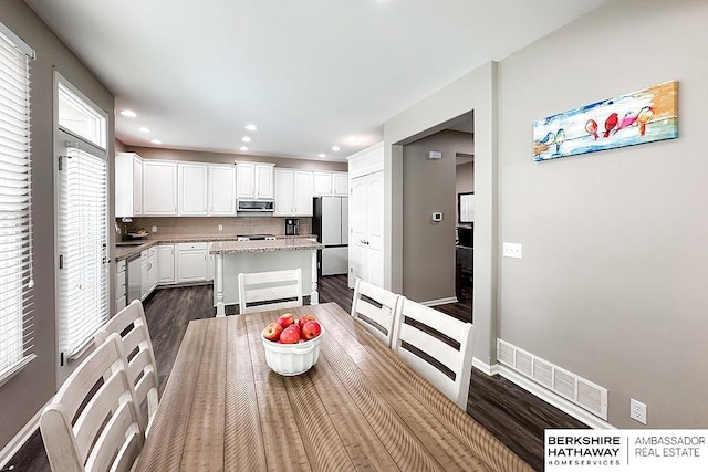 kitchen featuring visible vents, dark wood-style flooring, a kitchen island, white cabinetry, and appliances with stainless steel finishes