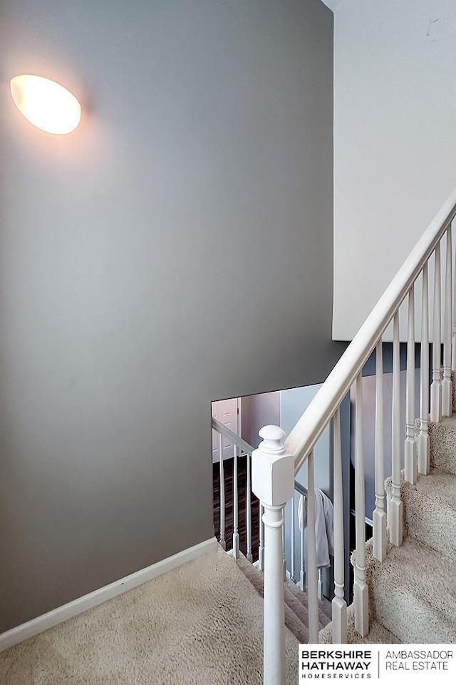 stairway featuring baseboards and carpet flooring