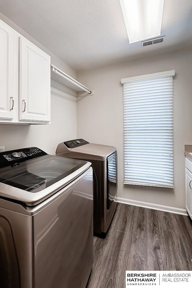laundry area with visible vents, cabinet space, independent washer and dryer, and dark wood-style flooring