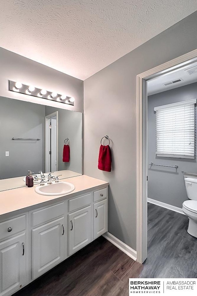 bathroom featuring toilet, visible vents, wood finished floors, and vanity