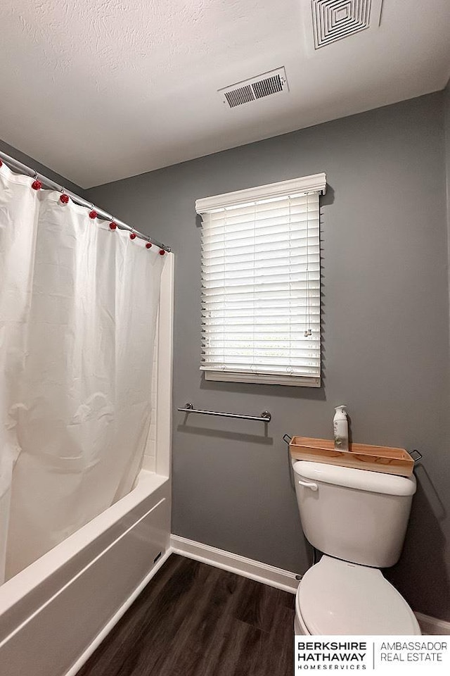 bathroom featuring visible vents, baseboards, wood finished floors, and toilet