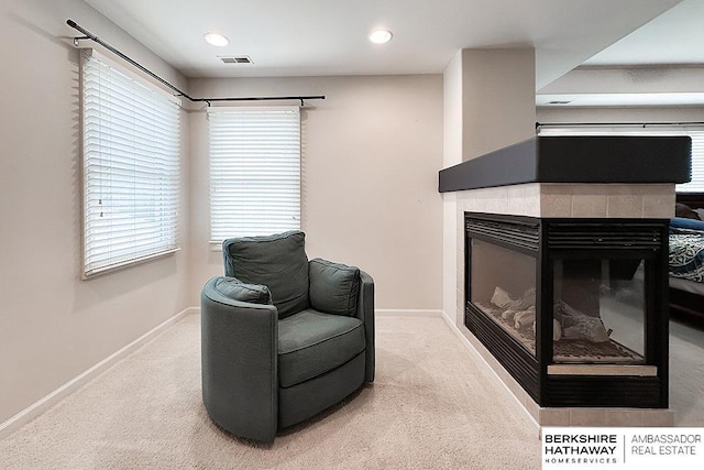 sitting room featuring visible vents, carpet flooring, baseboards, and a tiled fireplace