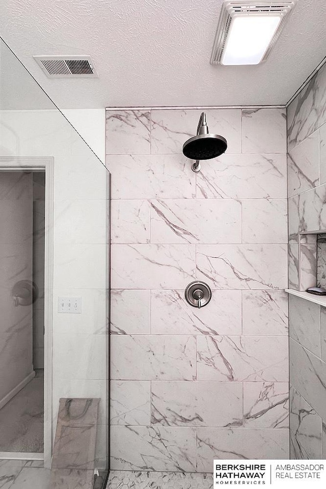 full bath with visible vents, marble finish floor, and tiled shower