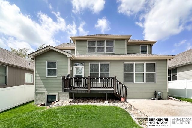 back of property featuring a lawn, fence, a wooden deck, and a patio area