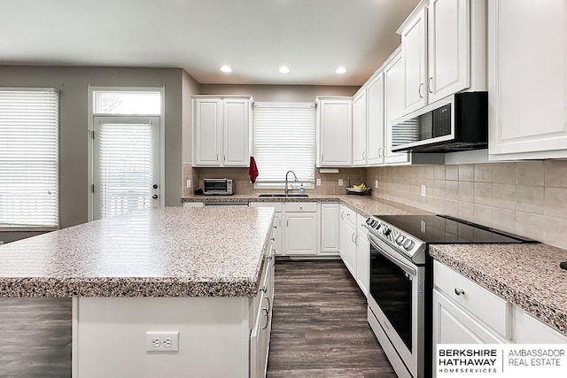 kitchen with a sink, stainless steel appliances, dark wood-style flooring, and a wealth of natural light