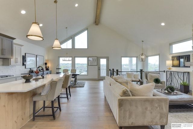 living area with beam ceiling, high vaulted ceiling, plenty of natural light, light wood-style flooring, and recessed lighting