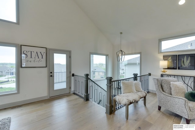 entryway featuring high vaulted ceiling, baseboards, light wood-style flooring, and visible vents