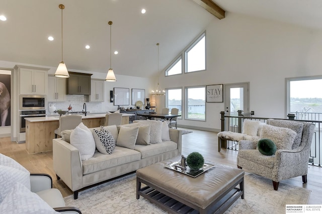 living area featuring high vaulted ceiling, recessed lighting, beam ceiling, and a chandelier