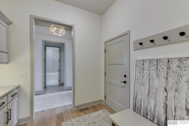 interior space featuring light wood-style floors, baseboards, and an inviting chandelier