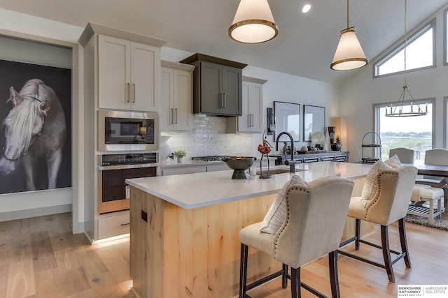 kitchen featuring light countertops, stainless steel appliances, a center island with sink, and a kitchen breakfast bar