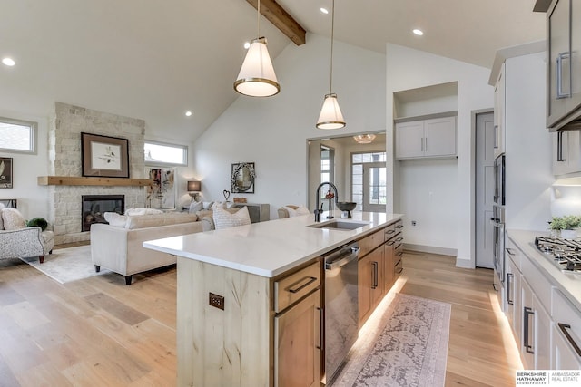 kitchen with appliances with stainless steel finishes, beam ceiling, a sink, high vaulted ceiling, and light wood-style flooring