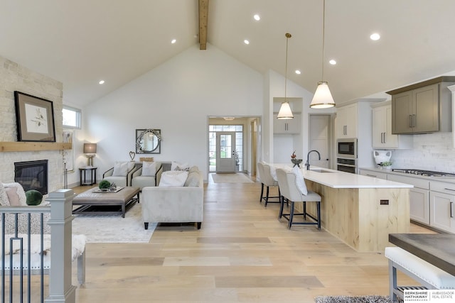 living area featuring plenty of natural light, a stone fireplace, beam ceiling, and high vaulted ceiling