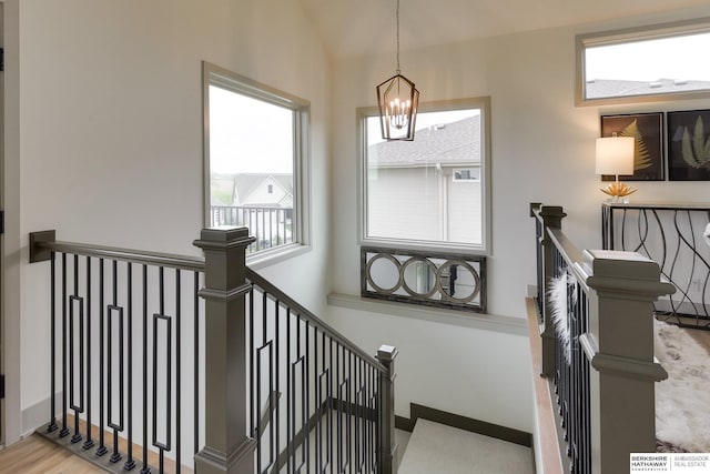 staircase featuring an inviting chandelier, wood finished floors, and lofted ceiling