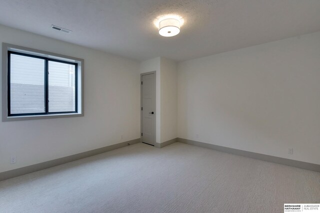 spare room featuring light colored carpet, baseboards, and visible vents