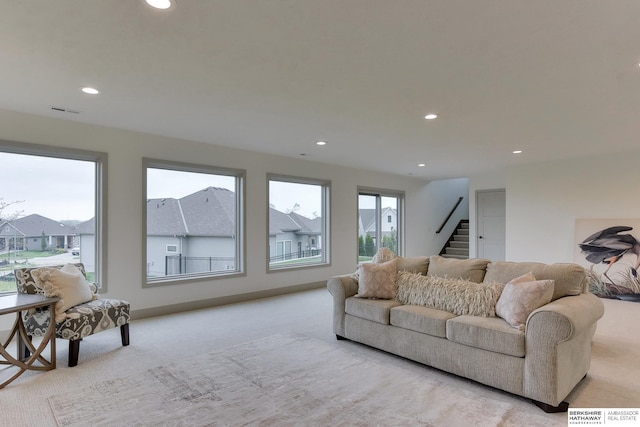living area featuring stairway, visible vents, recessed lighting, and light colored carpet
