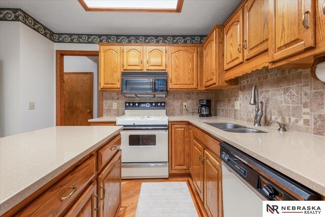 kitchen featuring tasteful backsplash, a sink, light countertops, white appliances, and light wood-style flooring