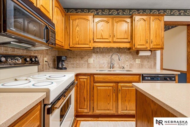 kitchen featuring electric range, black microwave, a sink, dishwasher, and light countertops