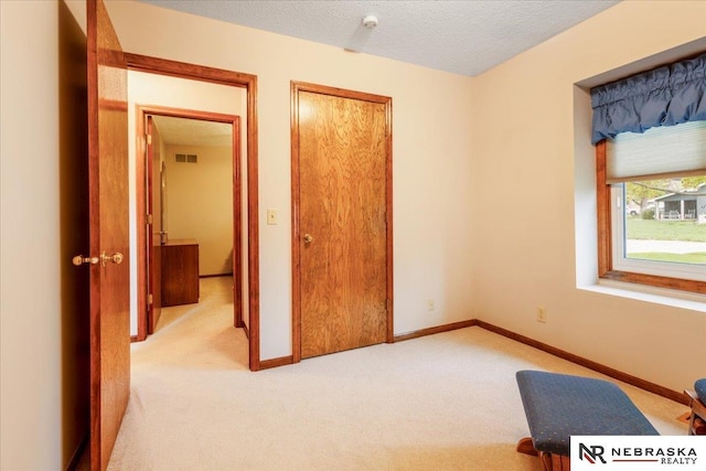 unfurnished bedroom featuring light colored carpet, baseboards, visible vents, and a closet