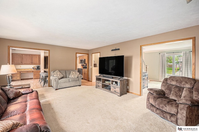 living area featuring baseboards and light carpet
