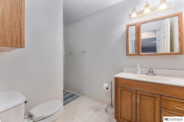 bathroom with toilet, baseboards, and vanity