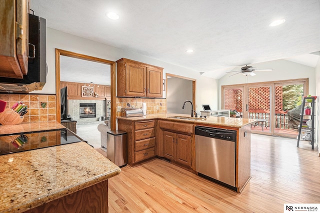 kitchen with a ceiling fan, appliances with stainless steel finishes, a sink, light wood finished floors, and a peninsula