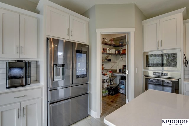 kitchen with light wood-style floors, light countertops, white cabinets, and stainless steel appliances