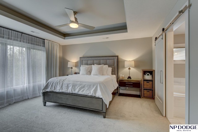 bedroom with a raised ceiling, light carpet, a barn door, and visible vents