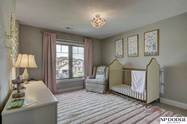 bedroom with a nursery area, carpet floors, a chandelier, baseboards, and visible vents