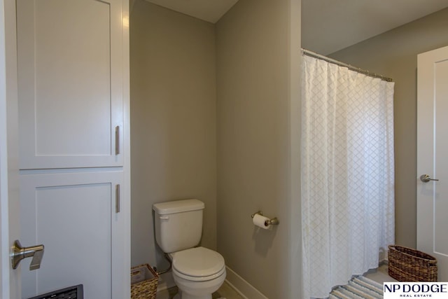 full bath featuring baseboards, a shower with shower curtain, and toilet