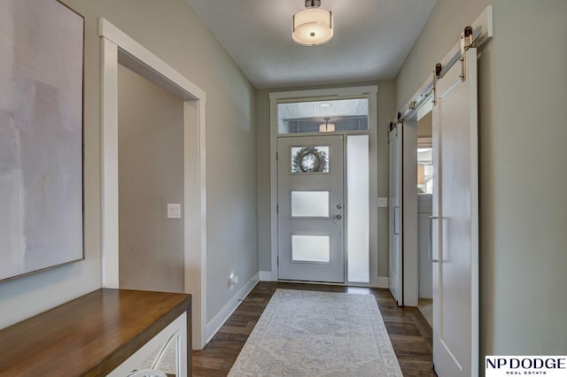 entryway featuring baseboards, a barn door, and dark wood finished floors
