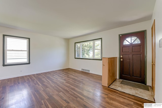 foyer entrance featuring baseboards, wood finished floors, and visible vents