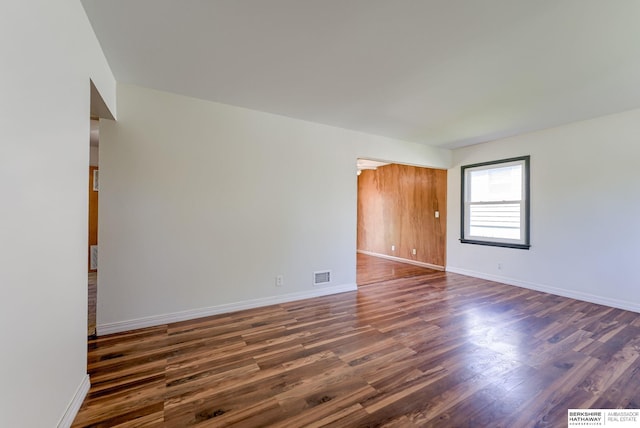 empty room featuring baseboards, visible vents, and dark wood-style floors