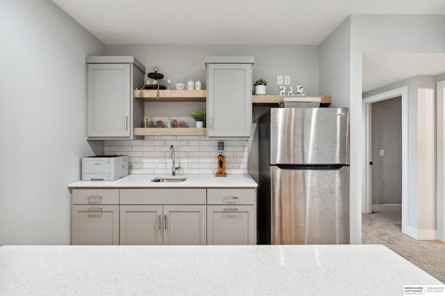 17026 Emma St, Bennington, NE 68007 - kitchen featuring open shelves, light carpet, a sink, freestanding refrigerator, and decorative backsplash