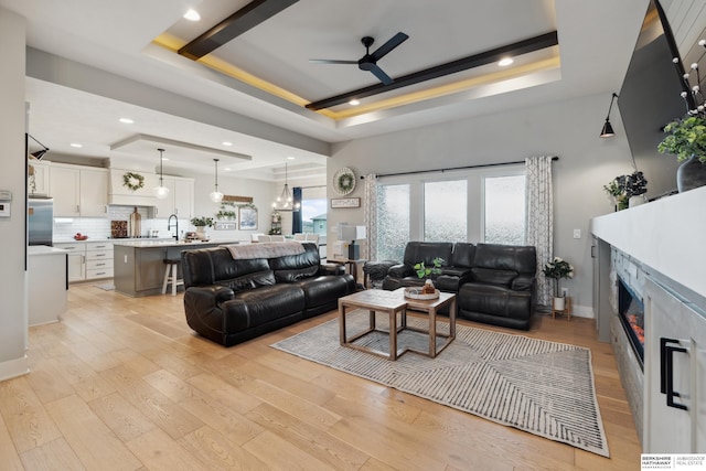 17026 Emma St, Bennington, NE 68007 - living area with ceiling fan, a tray ceiling, light wood-style flooring, and a premium fireplace