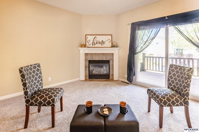 living area featuring baseboards, carpet, and a tile fireplace