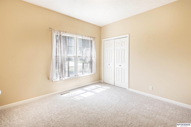 unfurnished bedroom featuring baseboards, carpet flooring, and a closet