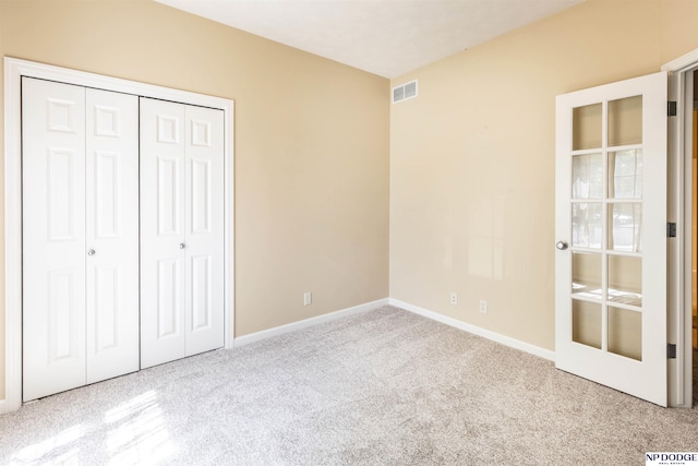 unfurnished bedroom with carpet floors, baseboards, visible vents, and a closet