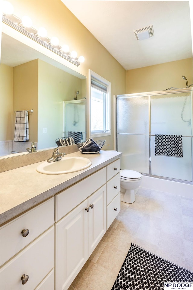 full bath featuring vanity, toilet, visible vents, and a stall shower