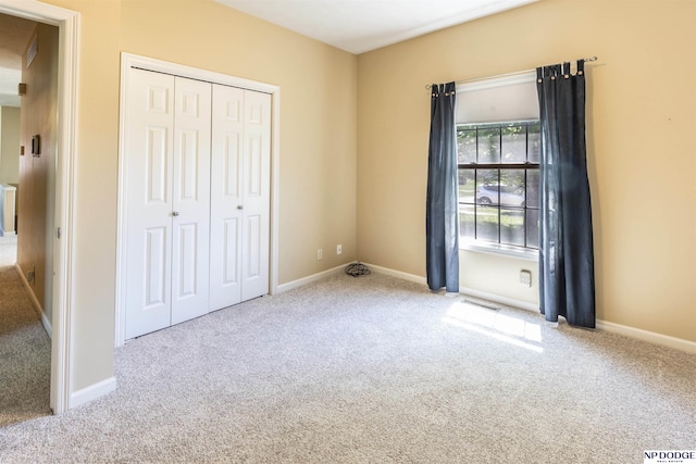 unfurnished bedroom featuring carpet floors, baseboards, a closet, and visible vents