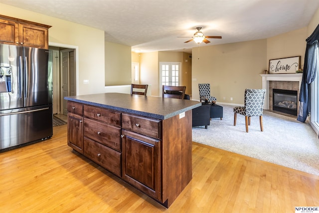kitchen with ceiling fan, dark countertops, light wood-type flooring, stainless steel fridge with ice dispenser, and open floor plan
