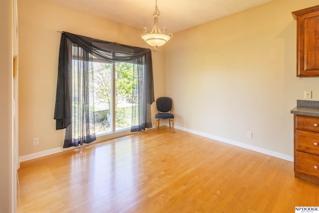 unfurnished dining area with light wood-style floors, baseboards, and visible vents