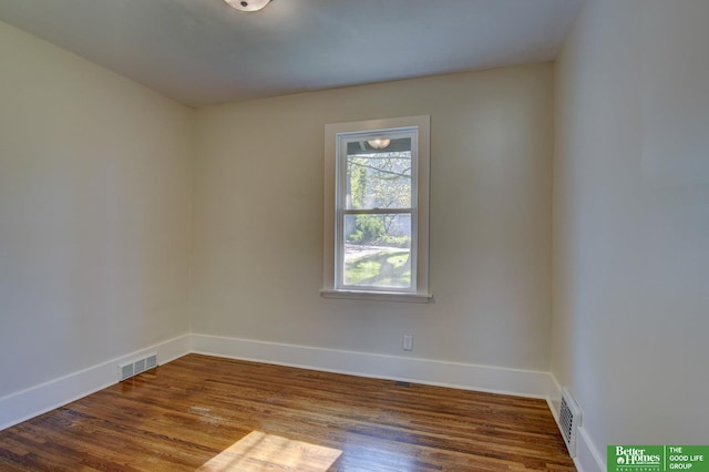 unfurnished room featuring baseboards, visible vents, and wood finished floors