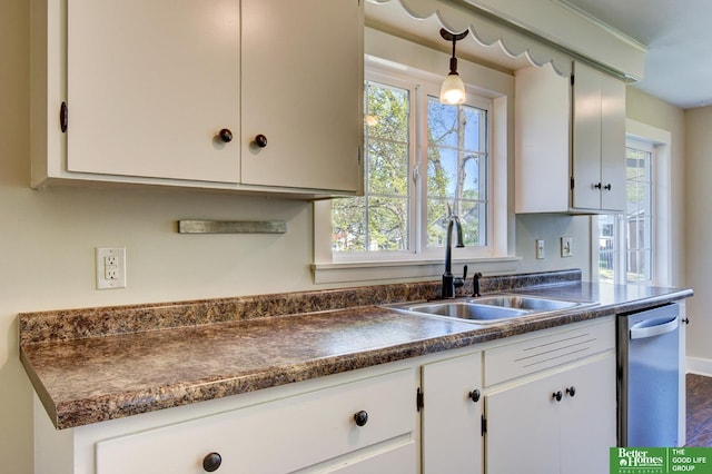 kitchen with white cabinetry, dark countertops, pendant lighting, and a sink