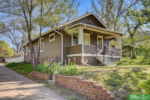 bungalow-style home featuring a front lawn, a porch, and fence