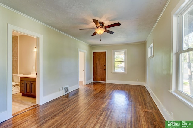 spare room featuring visible vents, wood finished floors, a ceiling fan, and ornamental molding