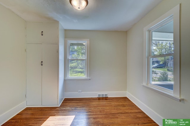 unfurnished bedroom featuring baseboards, visible vents, and wood finished floors