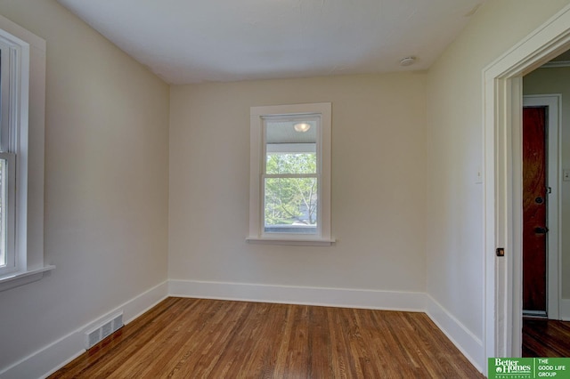 empty room featuring baseboards, dark wood-style flooring, and visible vents